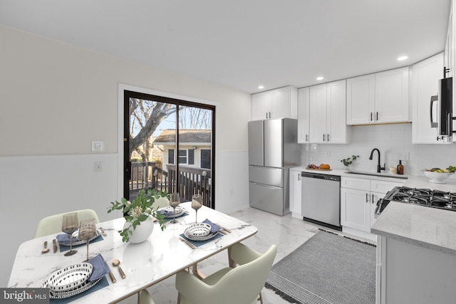 kitchen with white cabinetry, sink, light stone countertops, and appliances with stainless steel finishes