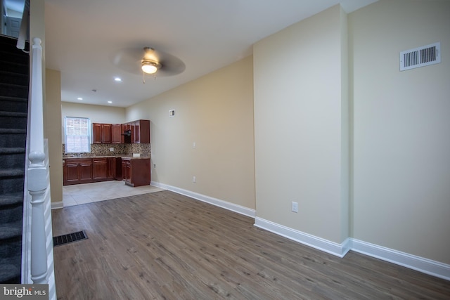 interior space with backsplash, ceiling fan, and light wood-type flooring