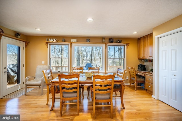 dining area with built in desk, a textured ceiling, and light wood-type flooring