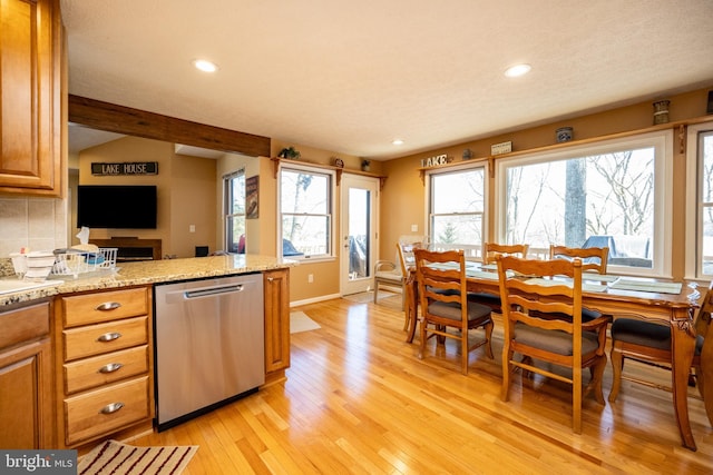 kitchen featuring light stone counters, tasteful backsplash, vaulted ceiling, stainless steel dishwasher, and light hardwood / wood-style floors