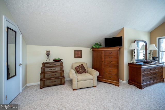 living area featuring vaulted ceiling, light carpet, and a textured ceiling