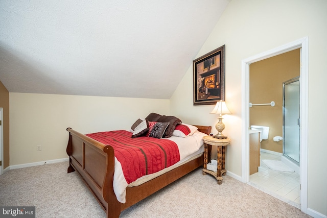 bedroom with light colored carpet, vaulted ceiling, and ensuite bath