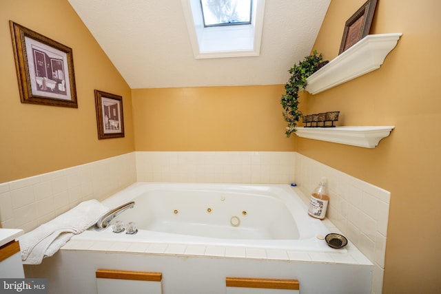 bathroom featuring lofted ceiling with skylight, a textured ceiling, and tiled tub