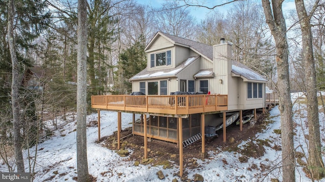 snow covered rear of property featuring a wooden deck