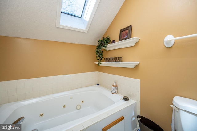 bathroom featuring toilet, vaulted ceiling with skylight, tiled bath, and a textured ceiling