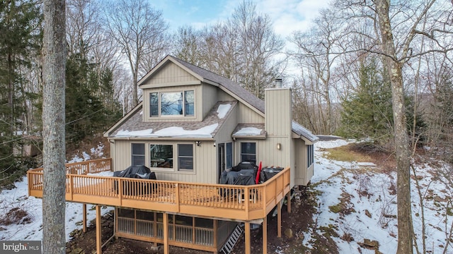 snow covered rear of property featuring a deck