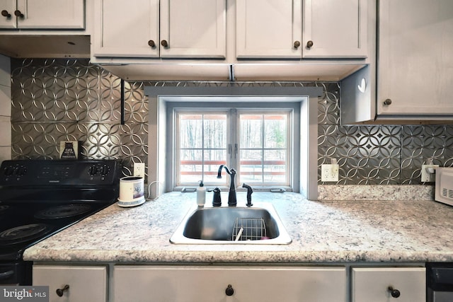 kitchen with decorative backsplash, black range with electric stovetop, and a sink