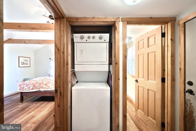 washroom featuring wood finished floors, laundry area, and stacked washer / dryer