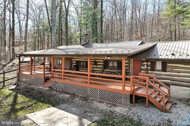 rear view of property featuring metal roof, log exterior, and a chimney