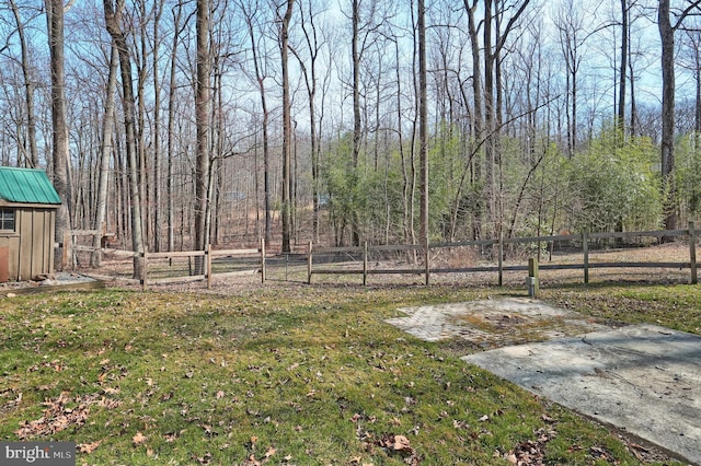 view of yard with a forest view, an outbuilding, and fence