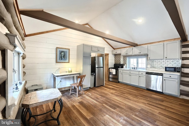 kitchen featuring dark wood-type flooring, light countertops, lofted ceiling with beams, appliances with stainless steel finishes, and a sink