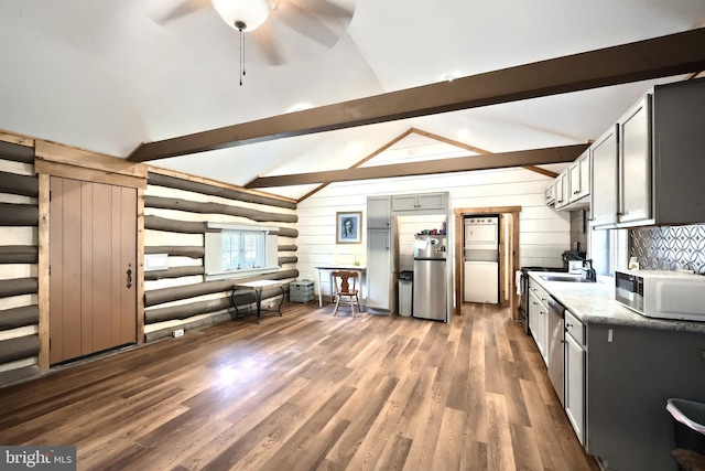 kitchen with white microwave, lofted ceiling with beams, freestanding refrigerator, and wood finished floors