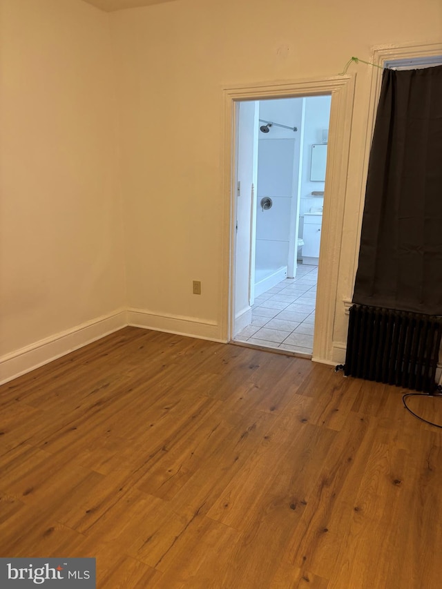 unfurnished room featuring radiator and light wood-type flooring