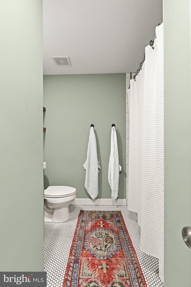 bathroom with walk in shower, tile patterned floors, and toilet