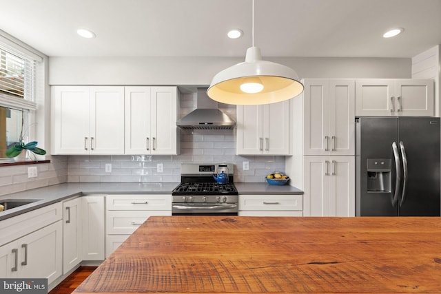 kitchen with white cabinetry, stainless steel appliances, butcher block countertops, and wall chimney range hood