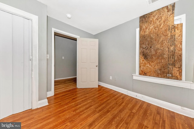 unfurnished bedroom featuring vaulted ceiling and light hardwood / wood-style flooring