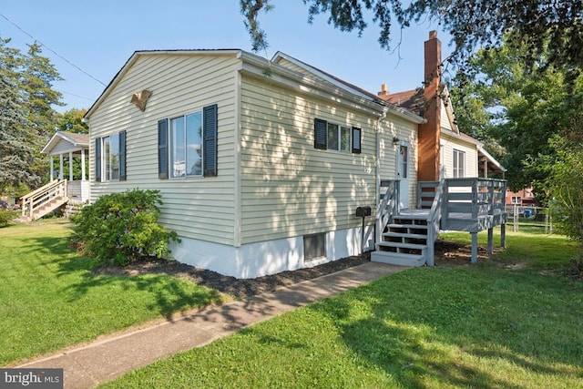 view of side of home featuring a wooden deck and a yard