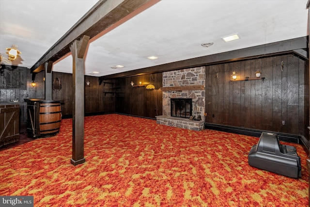 living room featuring a stone fireplace, carpet floors, beamed ceiling, and wood walls