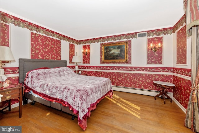 bedroom with hardwood / wood-style flooring and baseboard heating