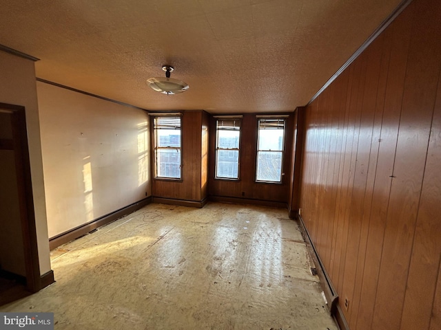 empty room with wooden walls and a textured ceiling