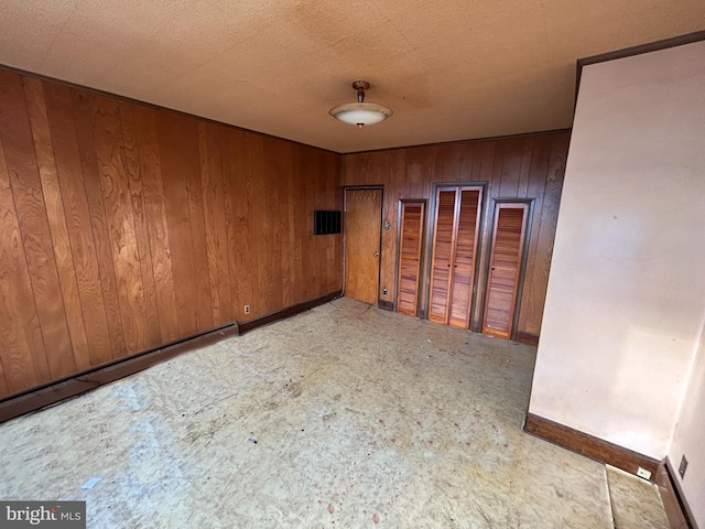 empty room with a textured ceiling and wood walls