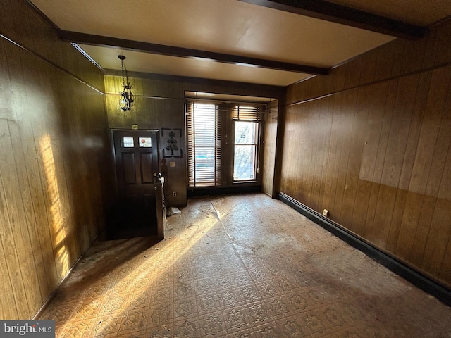 doorway featuring beam ceiling and wood walls