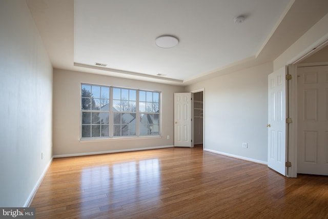 unfurnished bedroom featuring a raised ceiling and light wood-type flooring