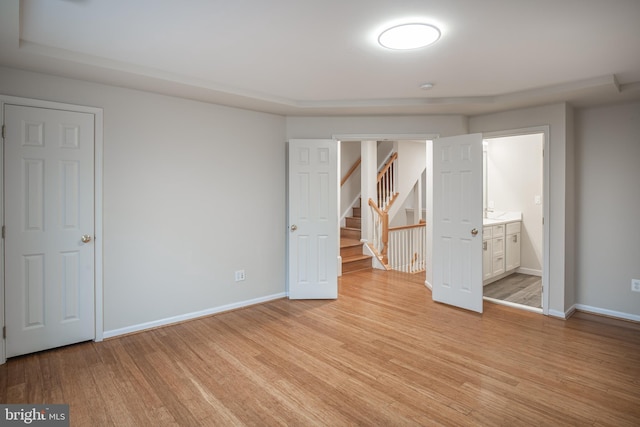 unfurnished bedroom featuring light wood-type flooring and ensuite bath