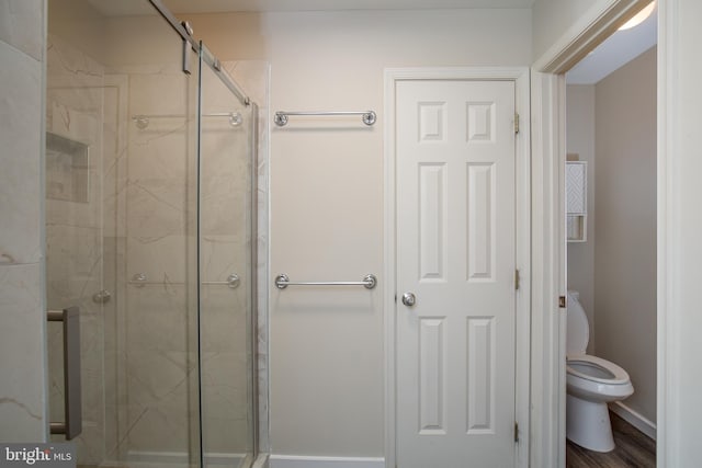 bathroom with a shower with shower door and toilet