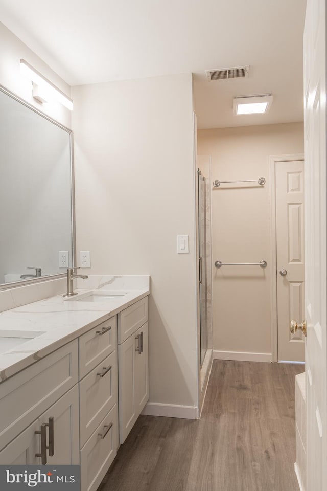 bathroom with vanity, hardwood / wood-style floors, and a shower with door