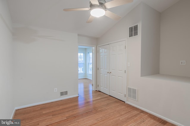 empty room with ceiling fan, vaulted ceiling, and light hardwood / wood-style flooring