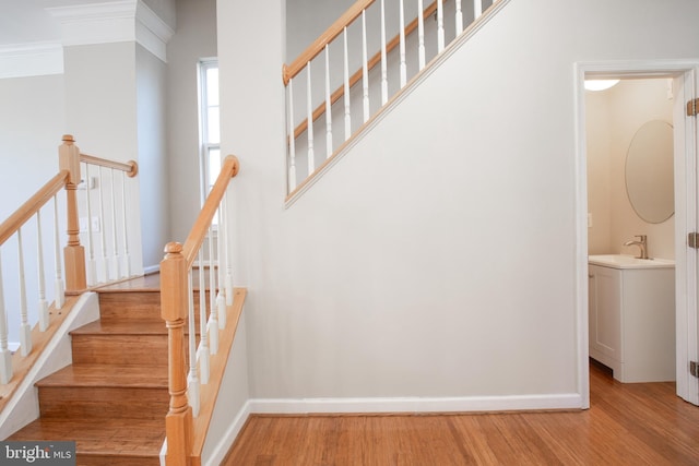 staircase with hardwood / wood-style flooring, ornamental molding, sink, and a towering ceiling