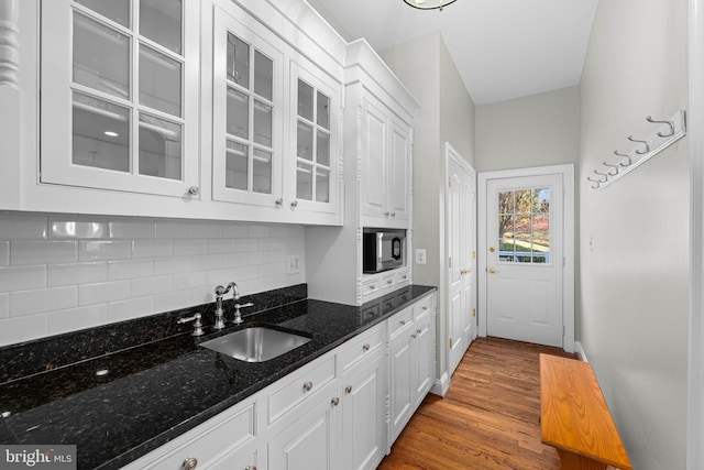 kitchen featuring dark stone countertops, sink, white cabinetry, and built in microwave