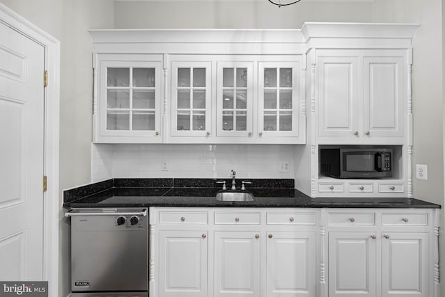 kitchen featuring dishwashing machine, sink, white cabinetry, dark stone countertops, and tasteful backsplash