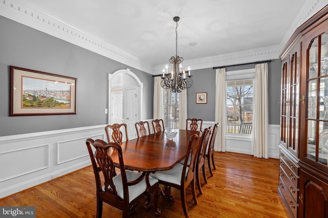 dining space with crown molding, a chandelier, and light wood-type flooring