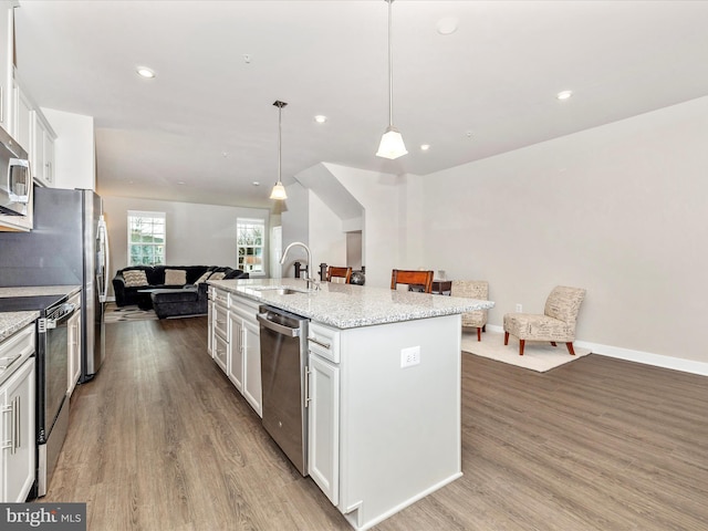 kitchen featuring sink, decorative light fixtures, appliances with stainless steel finishes, an island with sink, and white cabinets