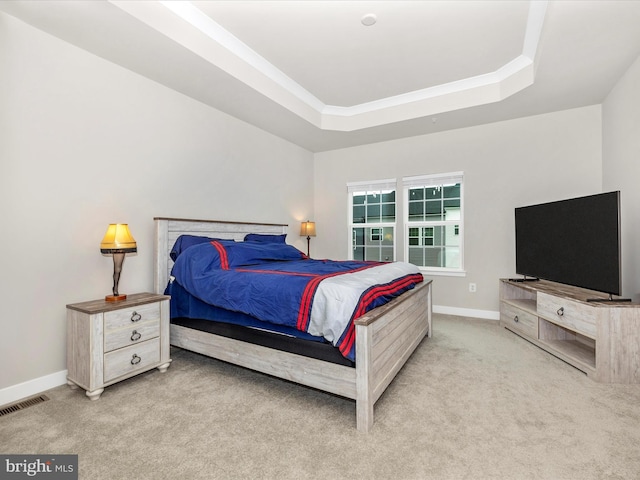 bedroom with a tray ceiling and light colored carpet