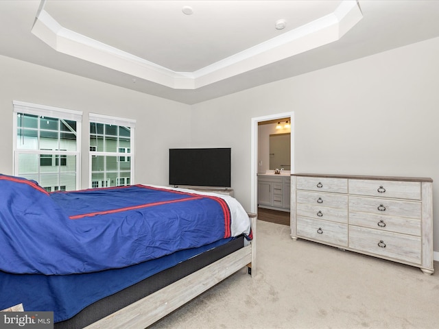 bedroom featuring crown molding, light colored carpet, connected bathroom, and a tray ceiling