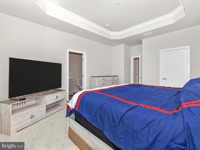 carpeted bedroom featuring a tray ceiling, ornamental molding, and ensuite bathroom