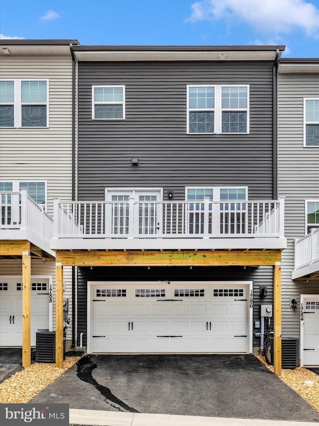 rear view of property featuring central AC and a garage