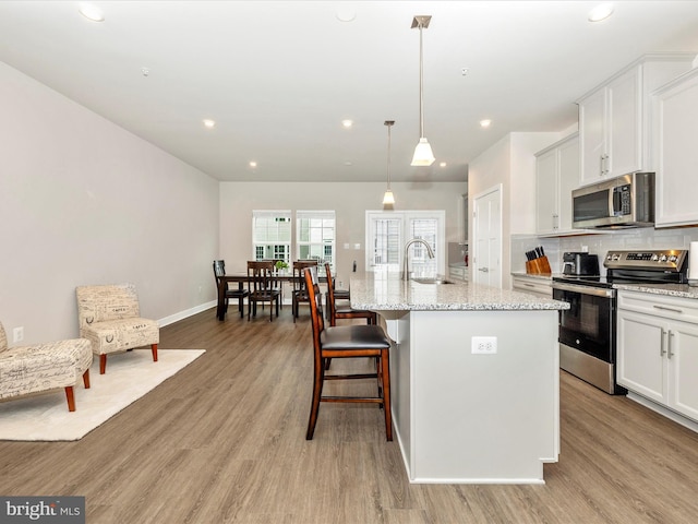 kitchen with a kitchen island with sink, sink, white cabinetry, and stainless steel appliances