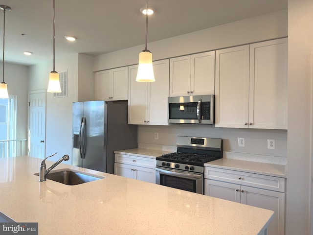 kitchen with white cabinetry, sink, stainless steel appliances, and hanging light fixtures