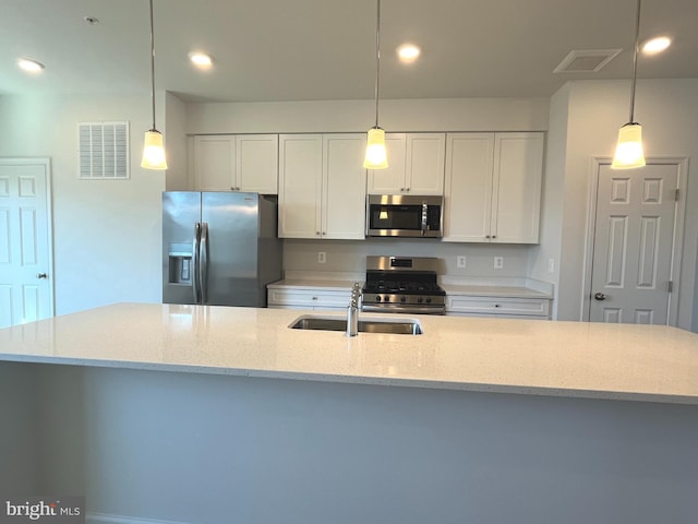 kitchen with white cabinetry, pendant lighting, light stone countertops, and appliances with stainless steel finishes