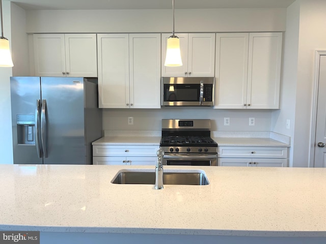 kitchen featuring pendant lighting, sink, stainless steel appliances, and white cabinets