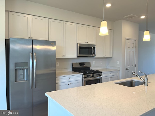 kitchen with sink, decorative light fixtures, stainless steel appliances, light stone countertops, and white cabinets