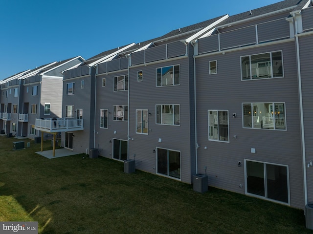 rear view of property featuring central AC and a lawn