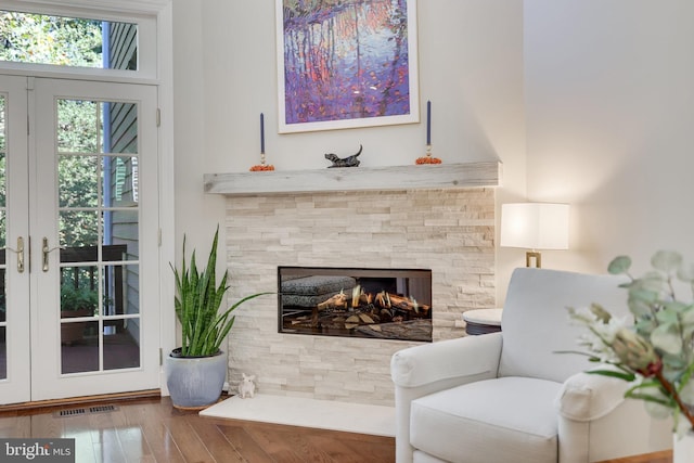 living area with french doors, a multi sided fireplace, and wood-type flooring