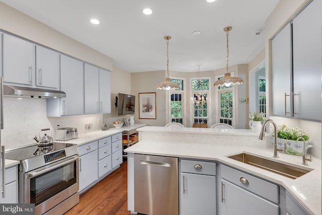 kitchen featuring sink, gray cabinetry, hardwood / wood-style flooring, appliances with stainless steel finishes, and pendant lighting