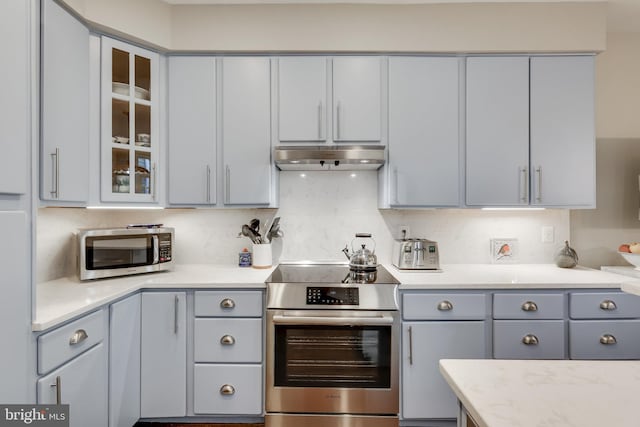 kitchen featuring gray cabinetry, backsplash, light stone countertops, and appliances with stainless steel finishes