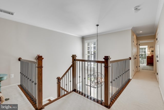 hall featuring crown molding, a chandelier, and light carpet